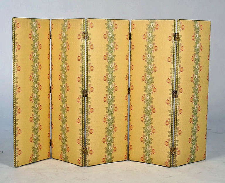 A five panel folding screen having yellow upholstery decorated with flowers