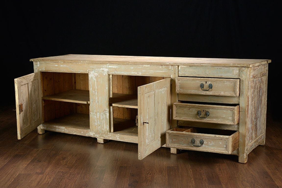 Exceptional antique pine buffet with four plank top, two doors with lock and key and three offset drawers.