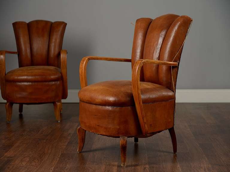 Pair of antique leather chairs with channeled backs and wood arms.