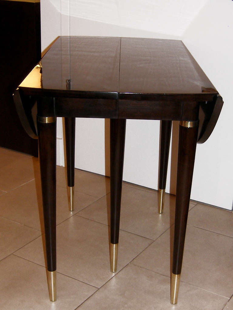 An ebonized walnut drop-leaf table with brass feet, by John Widdicomb.

American, circa 1960s

With original label - the table comes with 4 leafs and can extend to 92 inch long.

In stock.