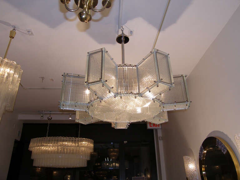 A large patterned glass chandelier with polished nickel frame and hardware.

Designed By Craig Van Den Brulle.

American, Circa 21st century.

In stock.