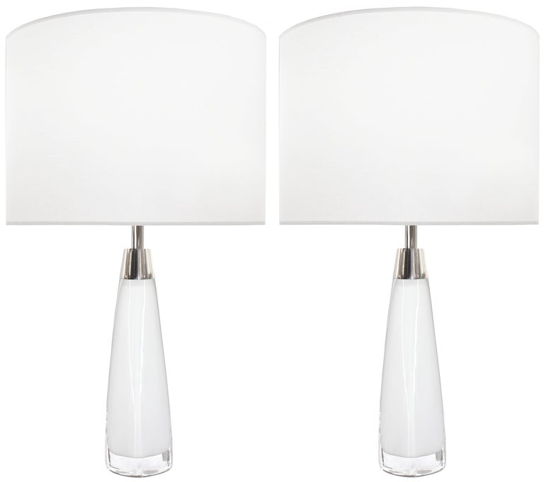 A pair of white glass lamps with thick clear glass casing with polished nickel hardware by Nils Landberg for Orrefors, 

Sweden, Circa 1960s.

Lamp Shades Are Not Included.

If you are interested in Lamp Shades, please email The Craig Van Den Brulle