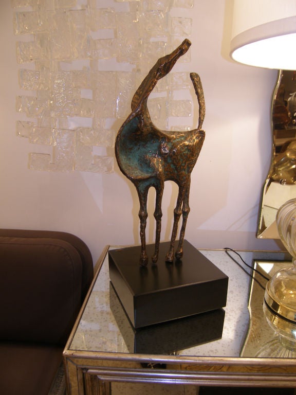 An elongated abstract bronze horse with green patina on blacken wood base. Signed Jere 1969, American