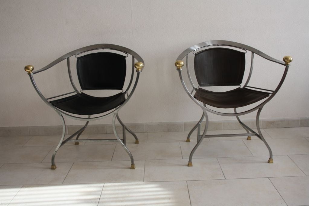 A pair of steel framed chair with bronze feet and arm detail with black leather seat and back by Maison Jansen, French C.1960's
