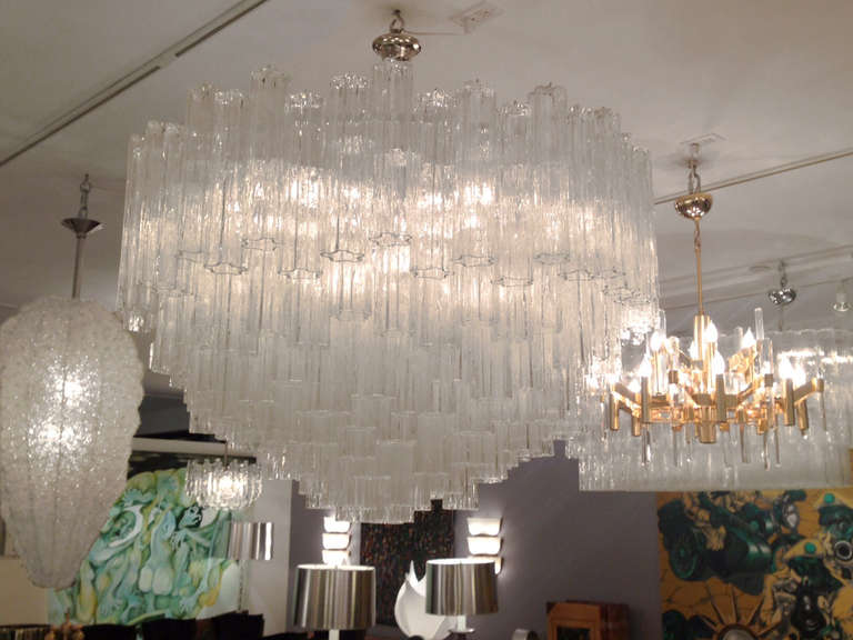 A glass chandelier consisting of multiple textured tubular glass hanging on a white painted frame with polished nickel hardware by Venini.

Italian, Circa 1970's

In stock.