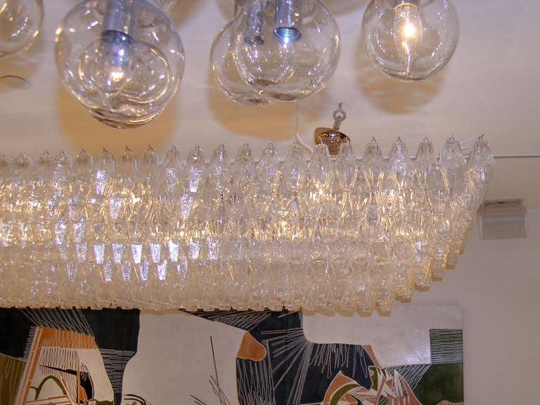 A large rectangular chandelier with tiered polyhedral clear glass on a white painted metal frame by Venini.

Italian, circa 1970s.