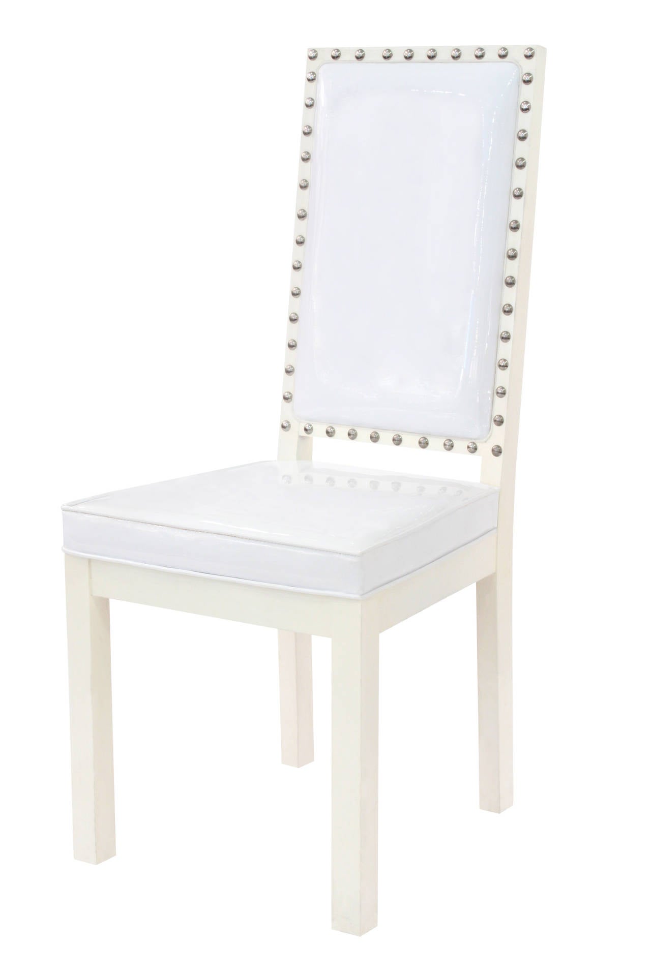 Ensemble de quatre chaises de salle à manger ou de jeu en laque blanche avec clous chromés et revêtement en cuir blanc à la manière de Tommi Parzinger, américain, années 1950.  Ces chaises sont très chics.