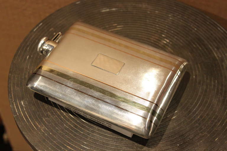 This is a beautiful example of the work being produced by Cartier in the 1930's. The entire flask is covered with linear deco engraving with alternating inlaid stripe of rose and green 14kt gold. The condition is excellent free of any dents or major