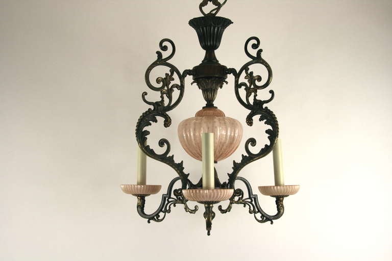 A three light dark patina brass supporting a gold dust Murano glass over a pale pink.  Three candelabra base bulb.