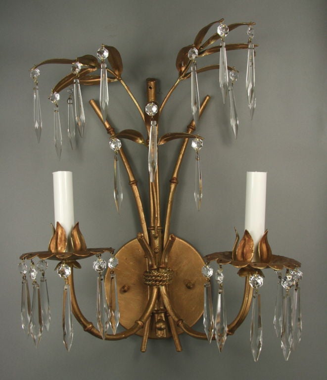 A pair of gilt palm leaf double-arm sconce dressed with crystal prisms.