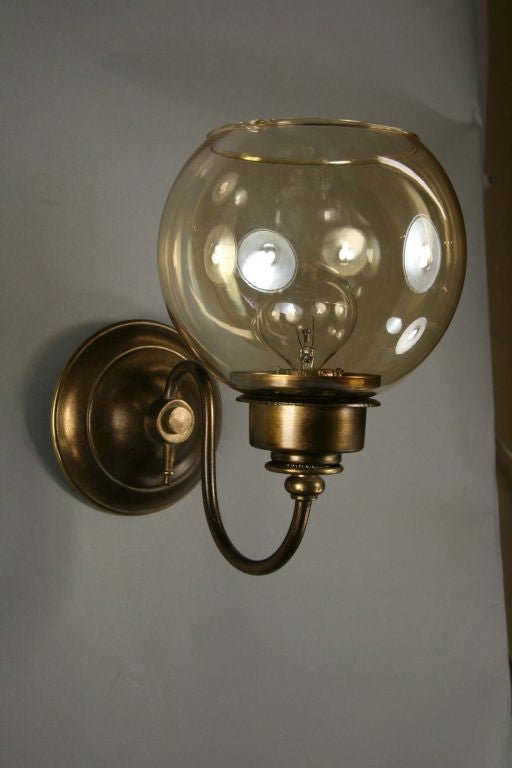 #2-1217a, a pair of darkened brass, single arm supporting an amber glass globe sconce.
