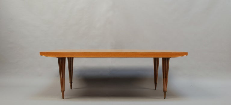 A large French Art Deco oak table with 4 ribbed brass conical legs and a parqueted top.
Possibility of two end extension leaves. 
Color of the legs is closer to top than it appears on the photos.
