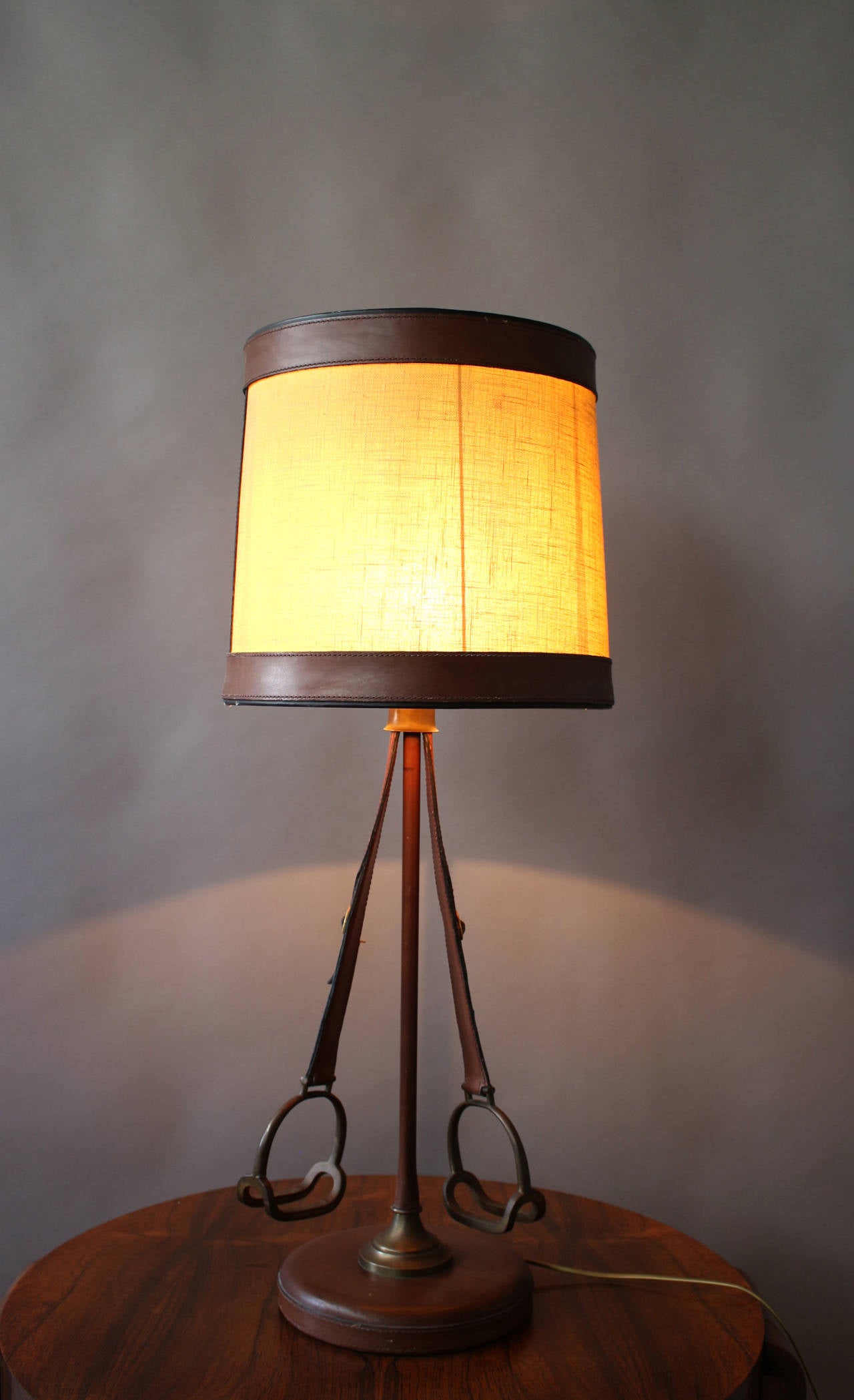 Fine and unusual French Art Deco leather and bronze stirrups table lamp with its original fabric and leather shade.