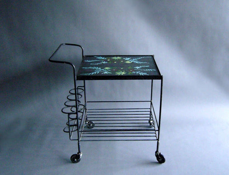 A French 1950s wrought iron rolling cart with a hand-painted and enameled stone top.