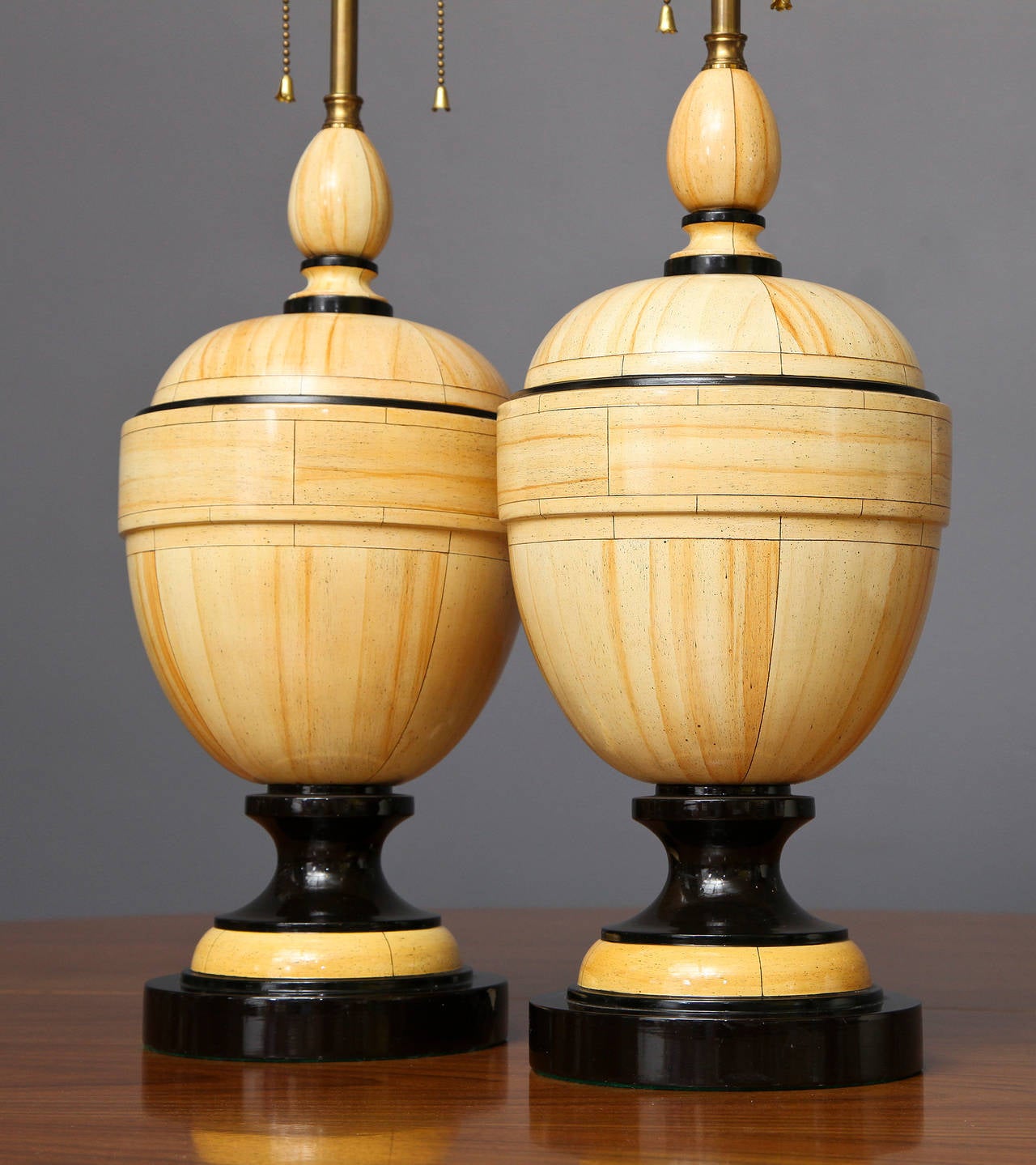 Jean Roger
Pair of table lamps in wood with a faux ivory and black lacquered finish and black penwork decoration of trompe l’oeil architectural details, 
French, circa 1970

Measurements: 28” H overall/ 16.75” H base x 7.5” diameter.