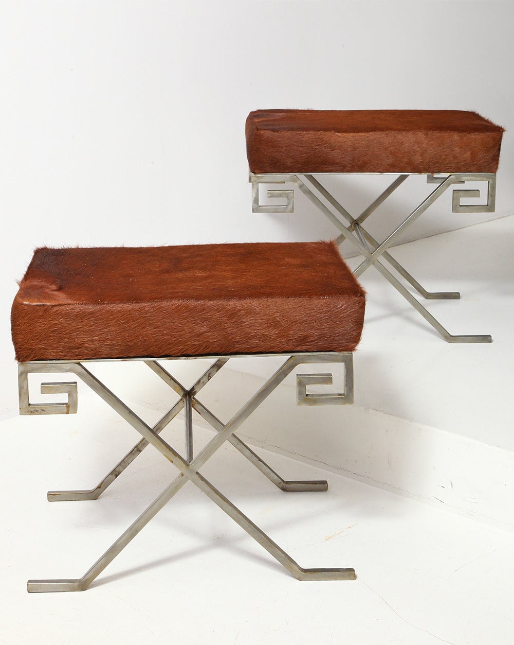 Pair of X-based stools or benches in polished steel with Greek key motif and upholstered pony skin seats.
French, circa 1950.