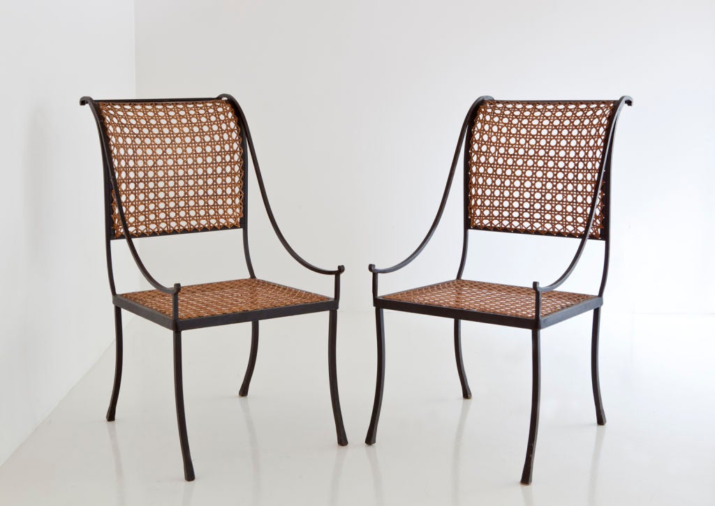 JOHN VESEY (1925-1992)
Pair of scrolling wrought-iron chairs with caned seats and backs.