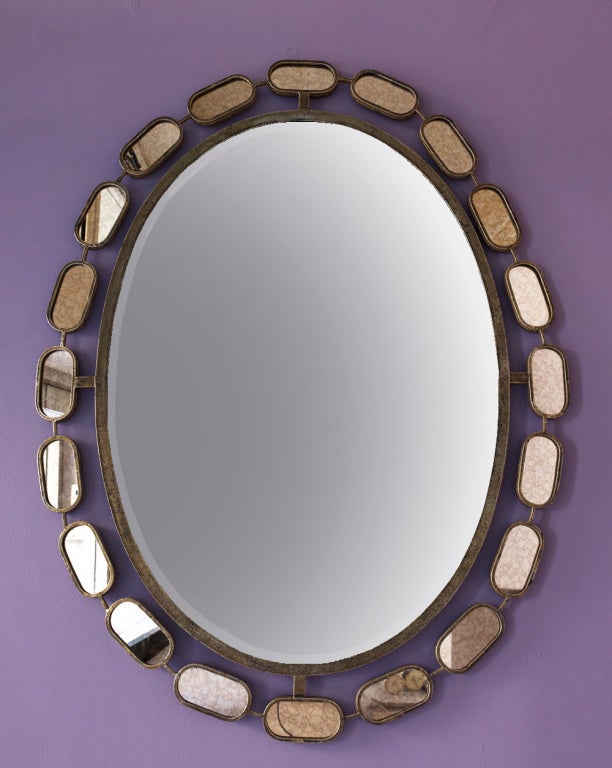 Wall mirror with beveled oval glass in patinated metal frame with antique mirror oval surrounds.