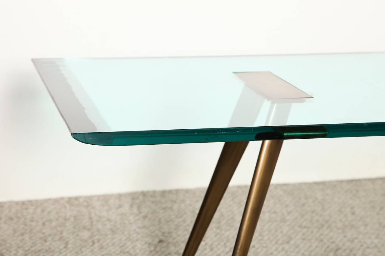Elegant table featuring a thick crystal lens top with beveled edges. Patinated brass splayed legs and top support. An incredible design, and rare model.
