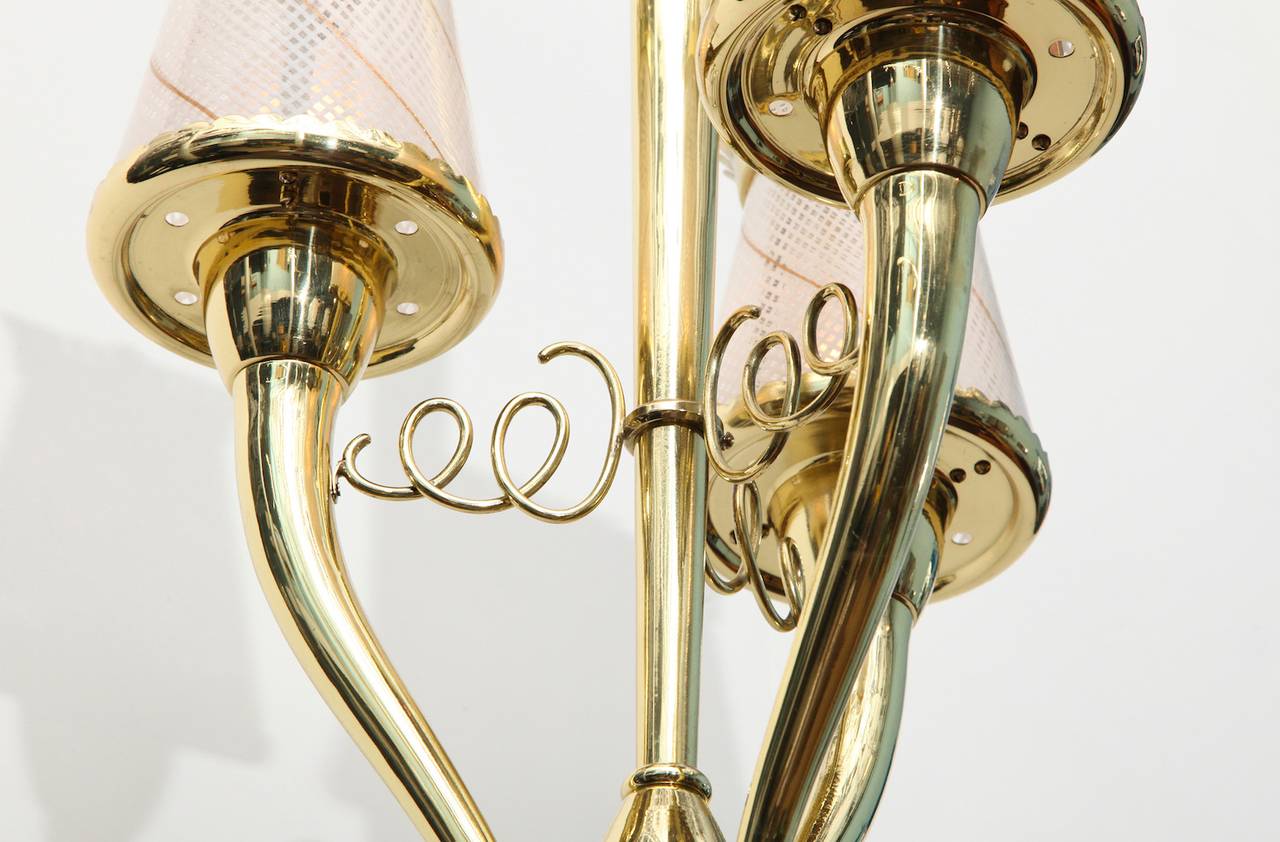 Beautiful hanging light in polished brass. Three Horn-shaped arms, each holding one candelabra socket. Murano glass filigrana shades, and crown shaped caps.