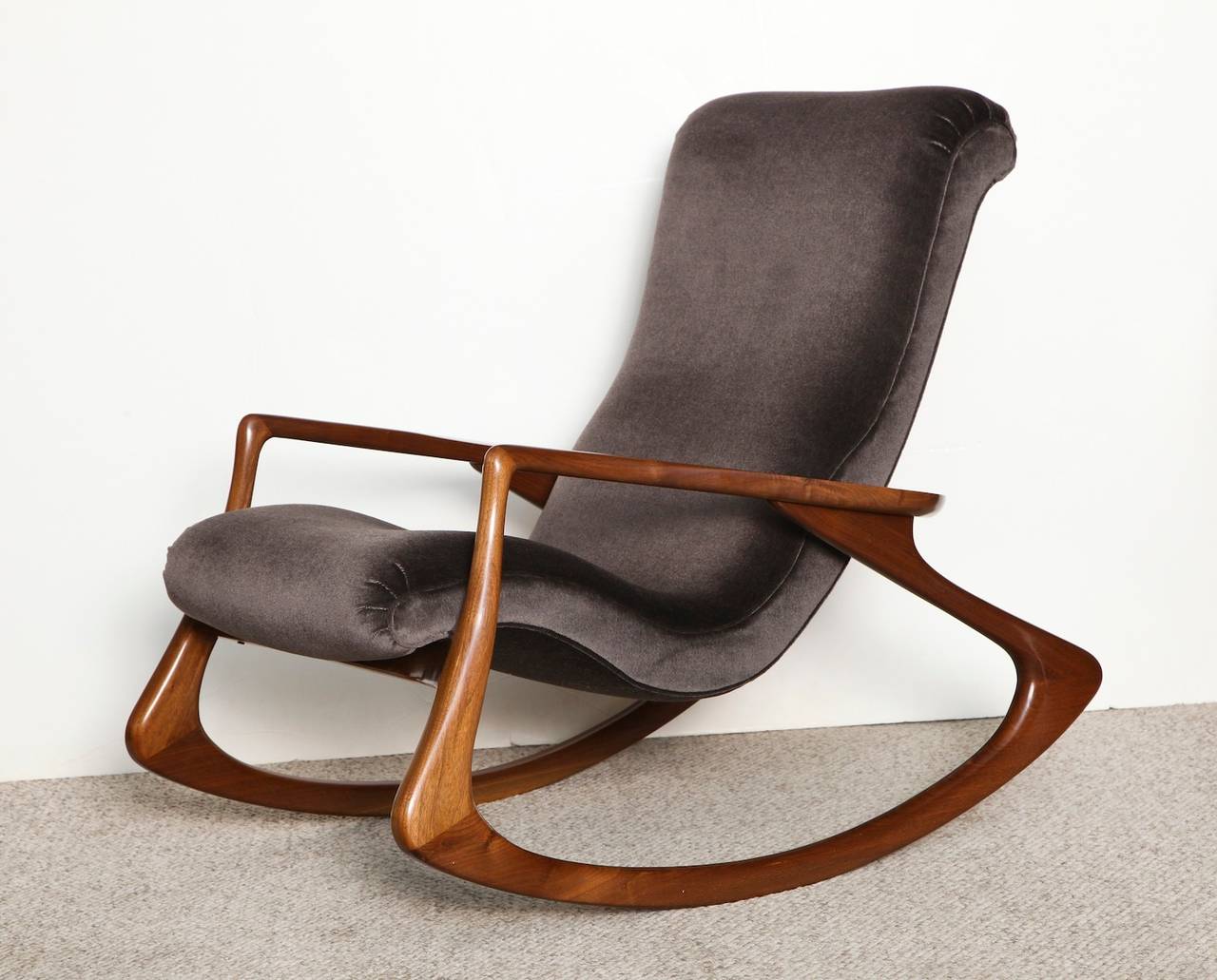 Contour rocking chair by Vladimir Kagan.  Sculpted walnut frame with dark velvet upholstery. A Classic Kagan design from 1953. This example dates from the mid-1970s.