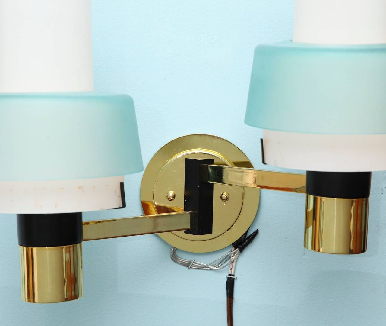 Pair of two-arm sconces, model 2079 by Stilnovo.  Great forms of black painted and polished brass. Acid-etched, white glass reflectors with pale blue, frosted-glass shades. Each sconce has two Edison sockets.