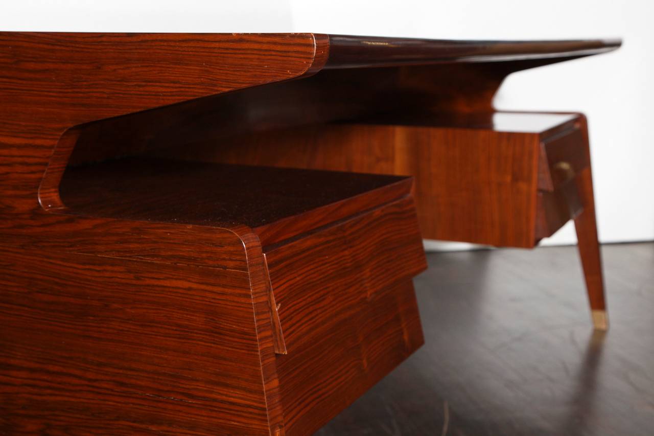 Unusual curved form, four drawers with shingled fronts and a floating top. Sculptural design with highly figured rosewood veneer and brass caps on the feet.