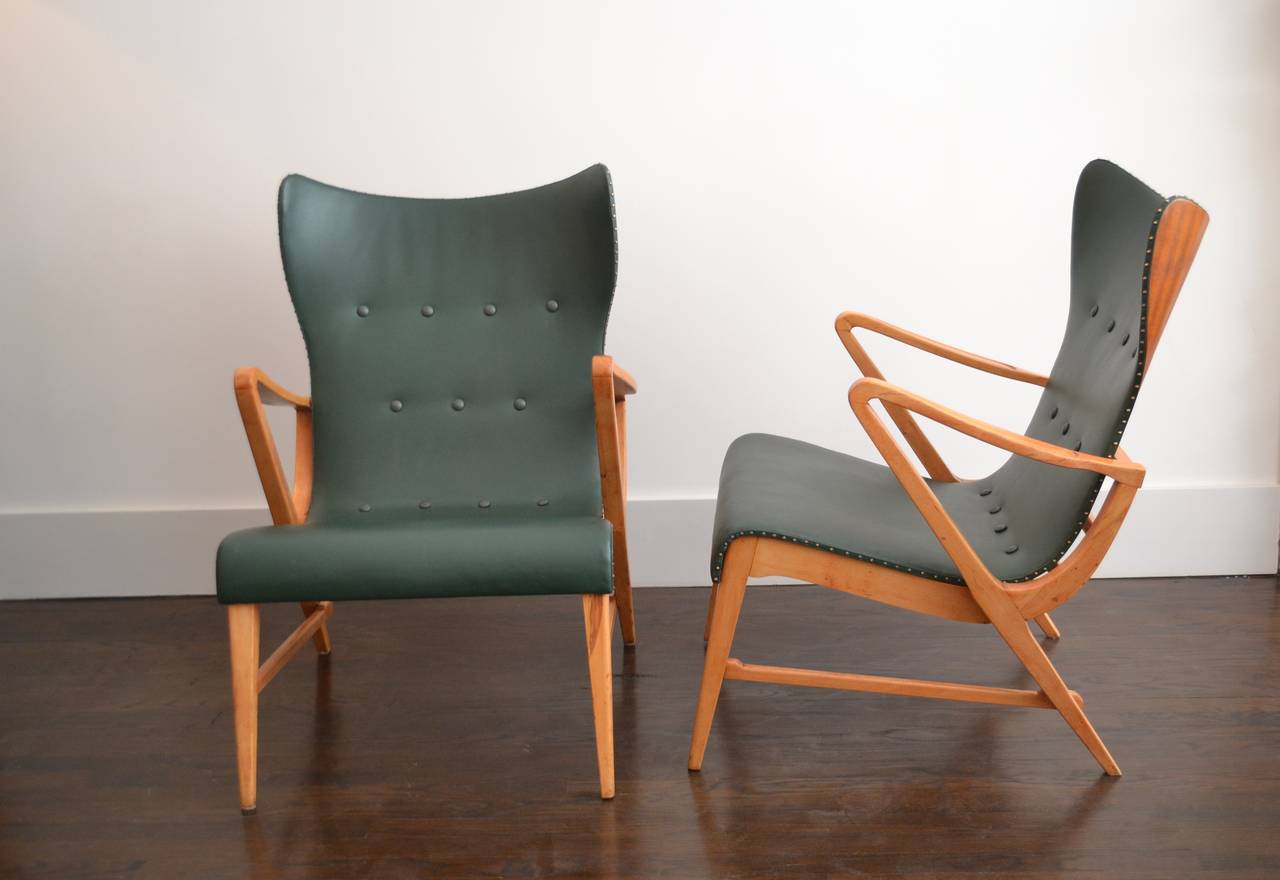 Pair of lounge chairs by Axel Larsson, Sweden, circa 1950.
Unusual whimsical lounge chairs designed by Swedish designer Axel Larsson.
Seats upholstered in dark green art leather with brass tacks. The backs are mahogany with supporting frame and