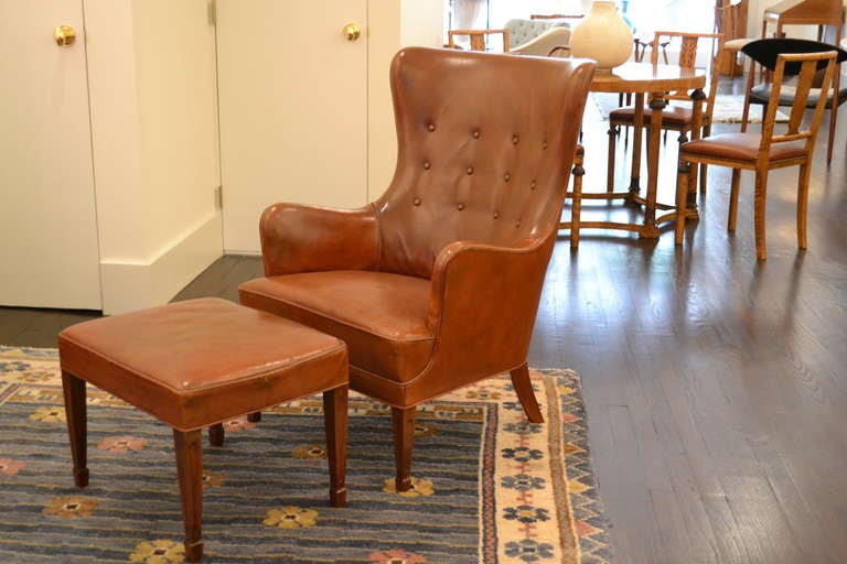 Beautiful chair and ottoman in original patinated leather by Frits Henningsen, Denmark ca. 1940. The leather is in excellent condition with no tears or stains. 
Chair measurements; 
37