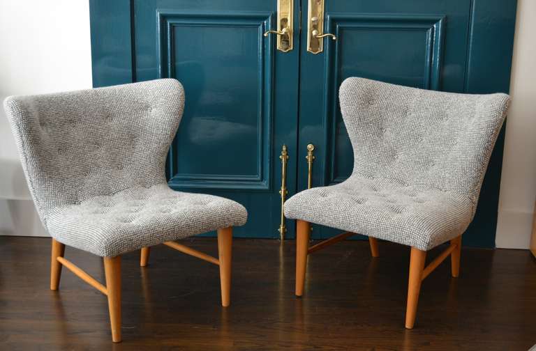 Elegant pair of lounge chairs by Swedish designer Elias Svedberg for NK (Nordiska Kompaniet), ca. 1950. Slipper - esque in shape, these chairs are extremely comfortable with a sculptural curve in the wide back that encircles you when you sit. Newly