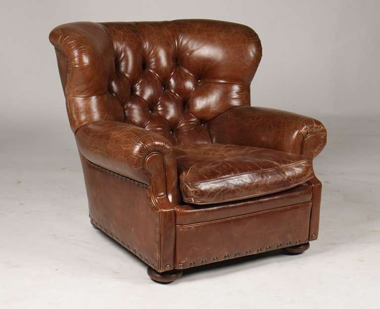 A labeled Ralph Lauren leather club chair having a tufted back on loose cushion seat all raised on bun feet. Ht: 36