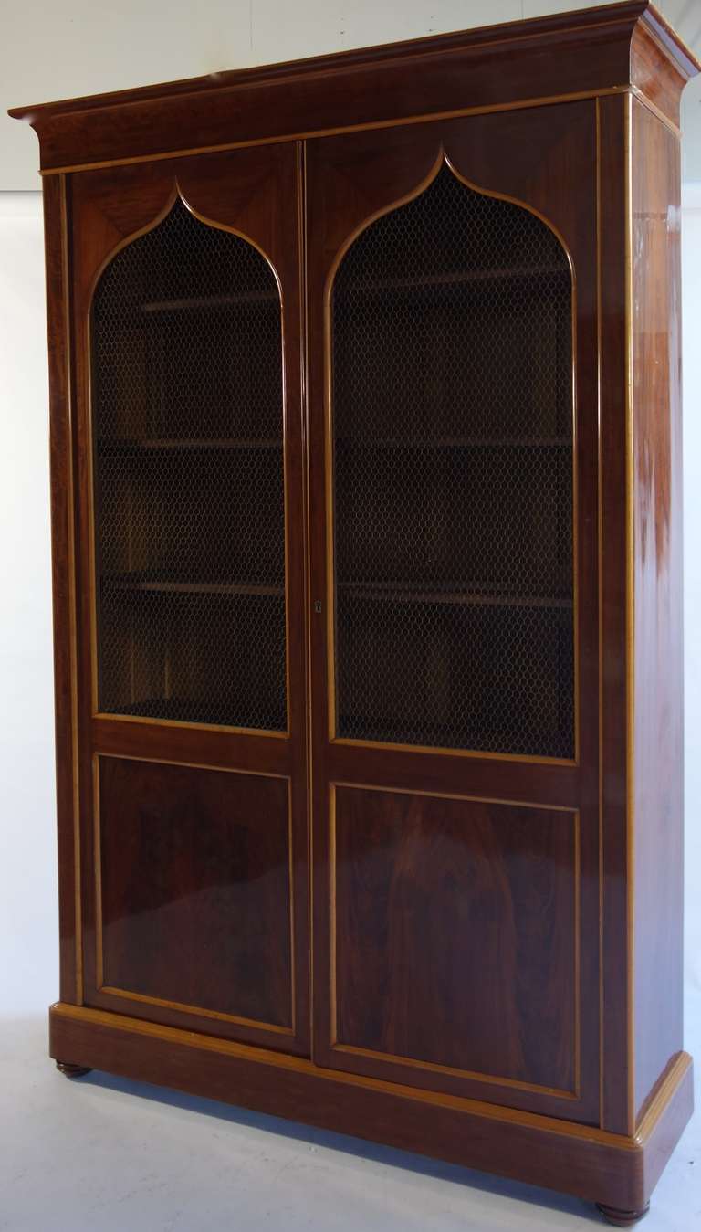 An extremely handsome French bookcase clad in gorgeous mahogany veneer and resting on bracket feet.