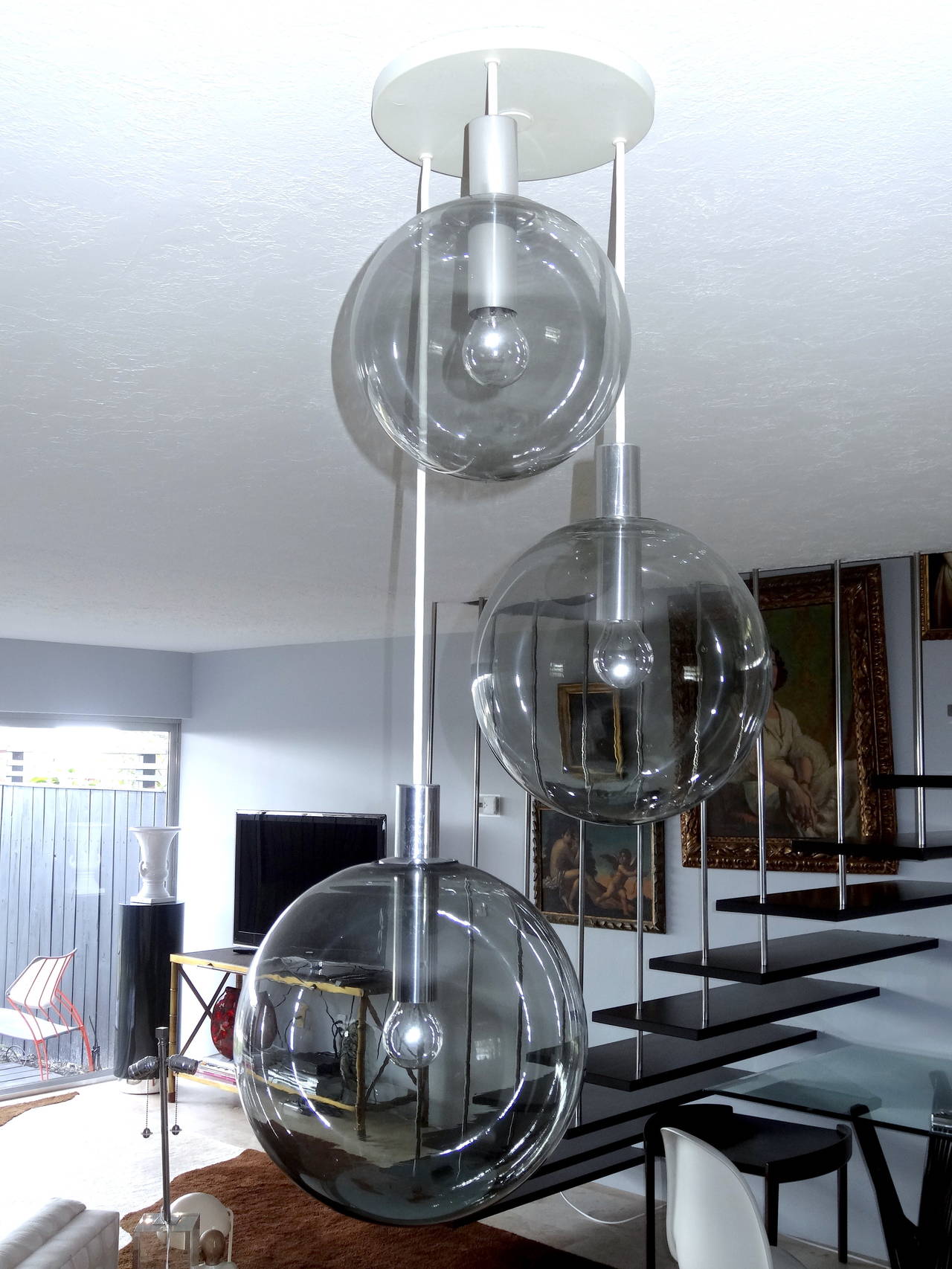 A simple modern designed three blown glass ball chandelier. This chandelier is of the period in design and complimented by the smoked color glass. Modern with a bit of elegance.
Possibly Italian.