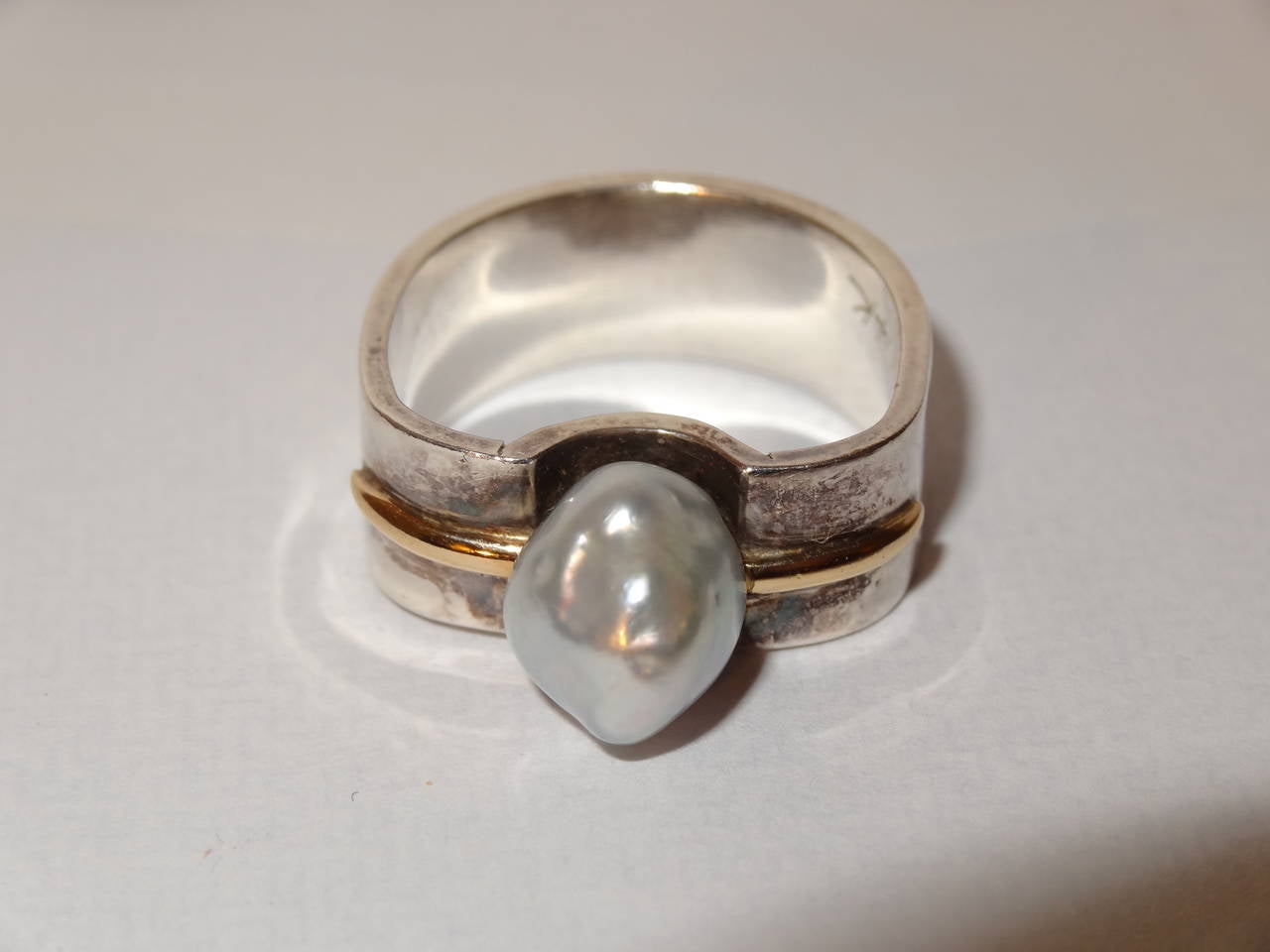 A modern ring by Kerber Design.
Ring is a modern organic formed shank of silver gold and set with a natural pearl. The pearl compliments the form and the mixed metal adds to the elegance of this piece.
Piece is signed and marked 14-karat and