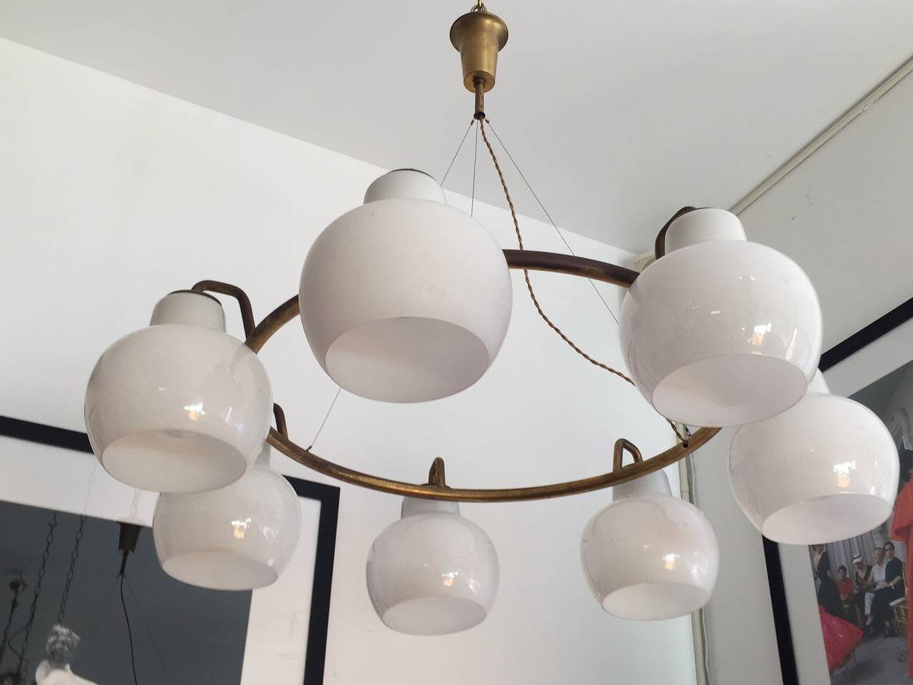 A large seven-light ring chandelier composed of an aged brass ring fixture and seven white opaline glass shades. Rewired. All original.