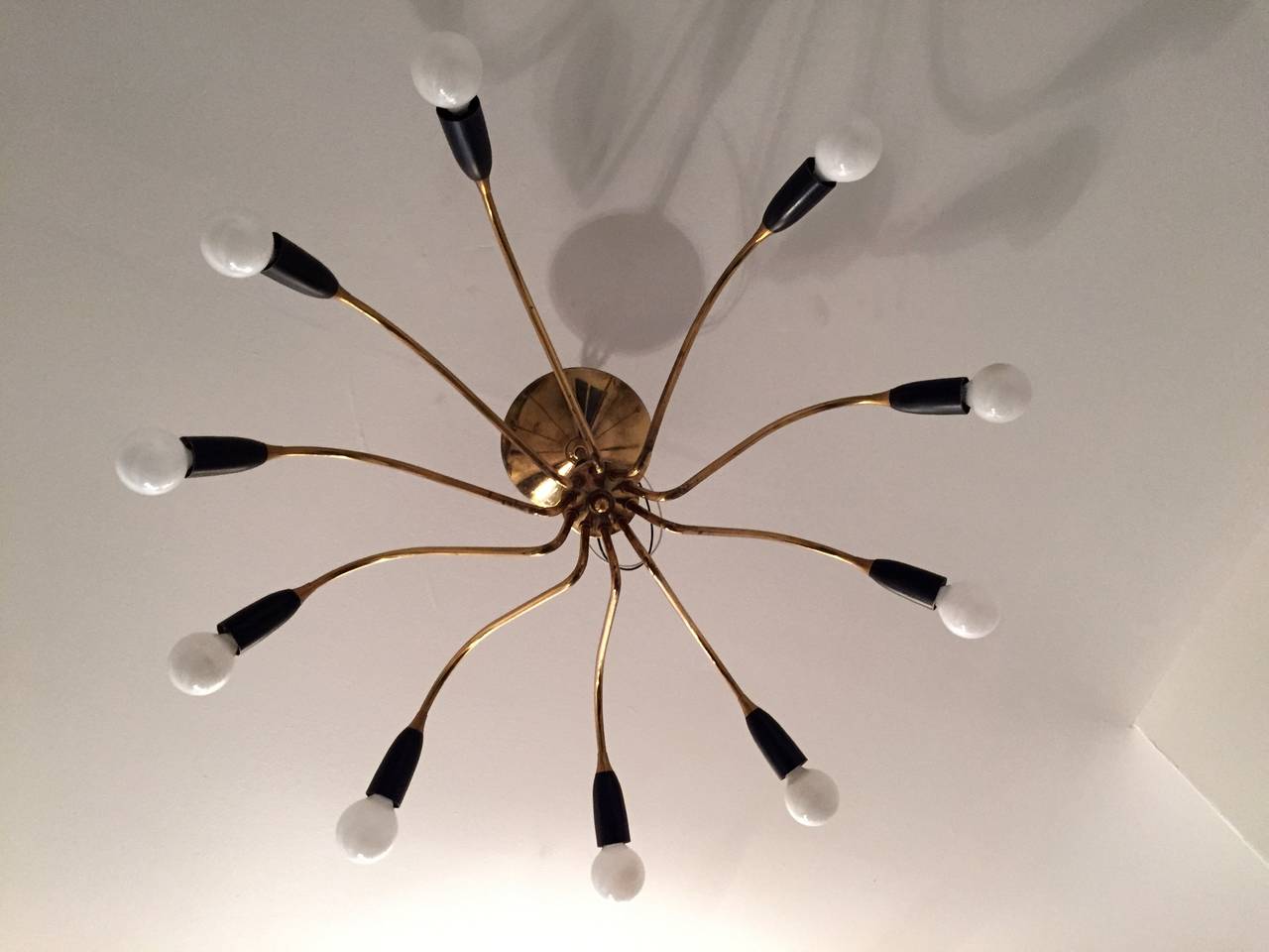 A 1950s Italian Mid-Century polished brass and black enamel ten-light chandelier. Rewired. We can extend the ceiling pole if needed.