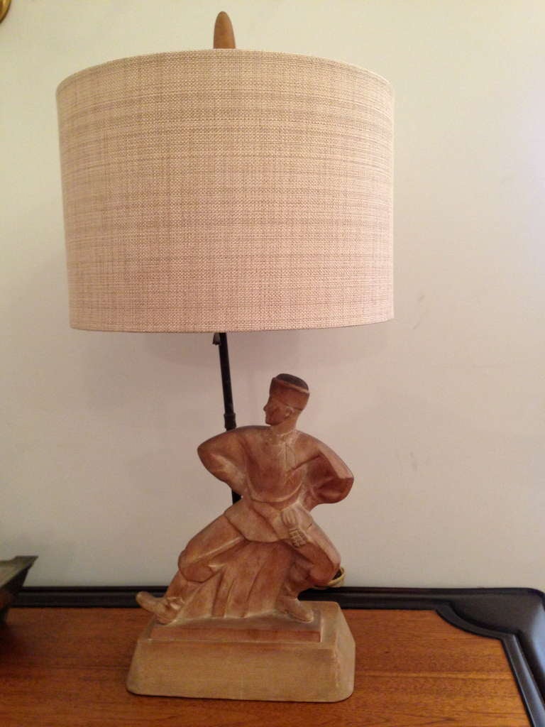 A great 1940s hand carved Russian dancer table lamp. The table lamp is done in a light wood with a slight paint wash to accent certain details. Carved on all sides. Rewired. Matching finial .The Russian figure is 12