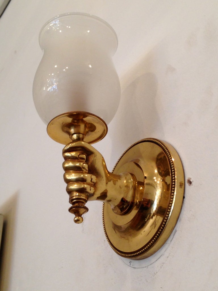 Pair of 1960s French decorative brass hand wall lights with white opaline glass shades.