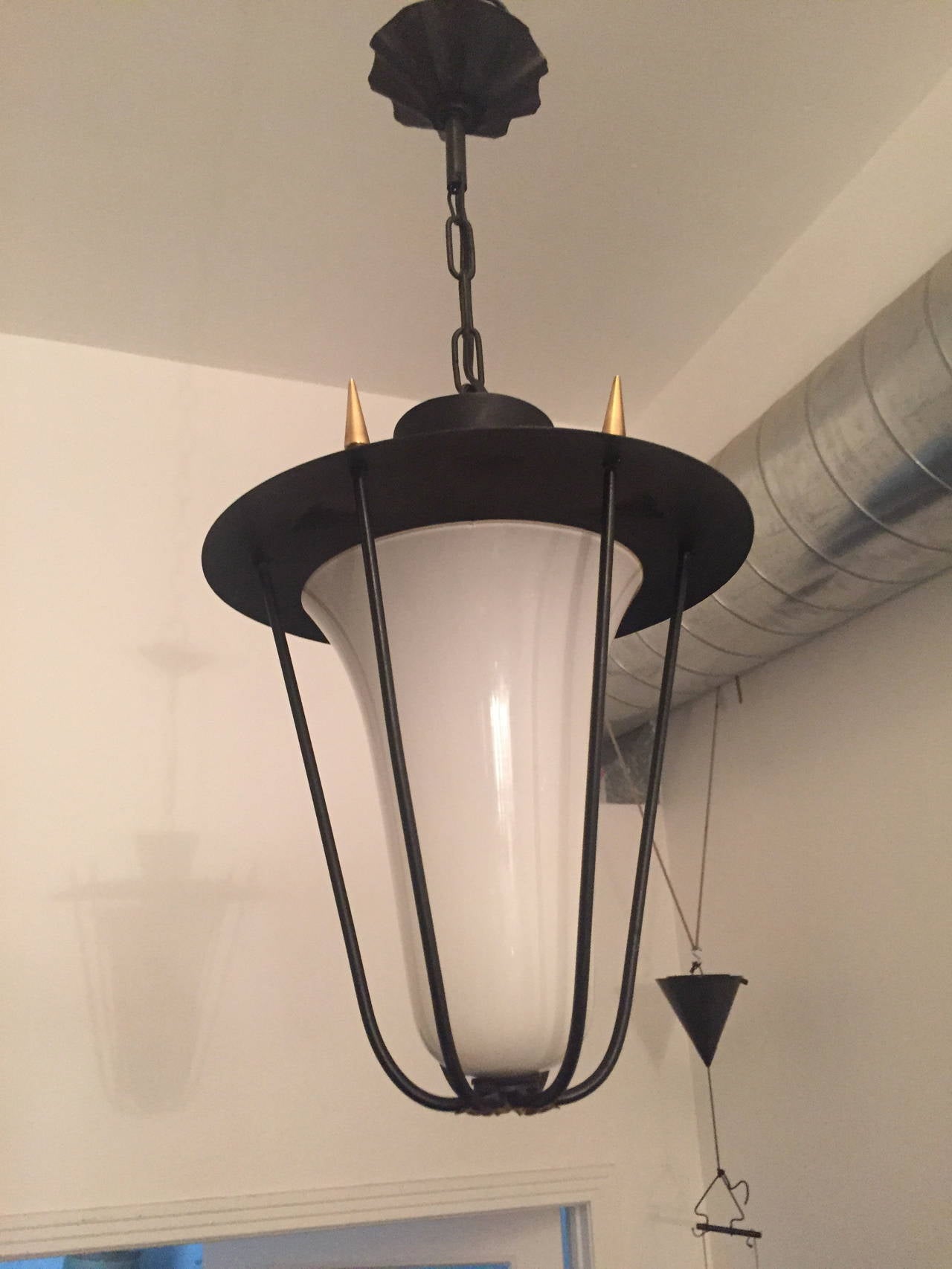 A great 1950s French hanging light done in matte black enamel and a gold decorative element body with a white opaline glass shade. 150 watt socket. The chain can be made longer if needed.