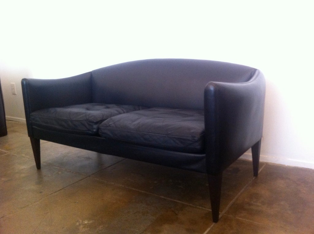 A classic Danish 1960s black leather with down cushions and sculptural rosewood legs and swooping modern lines by Danish master, Illum Wikkelsø.