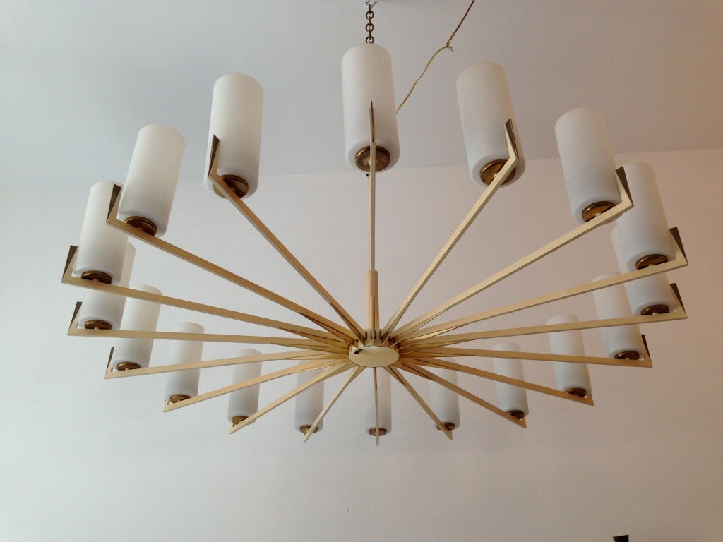 A rare pair of 1950's 18 light brass and white enamel fixtures with white glass shades by the famed Italian firm, Arredoluce.  Decorative brass fins form a sun pattern in the middle of the fixture. All original. Ceiling pole can be extend or a chain