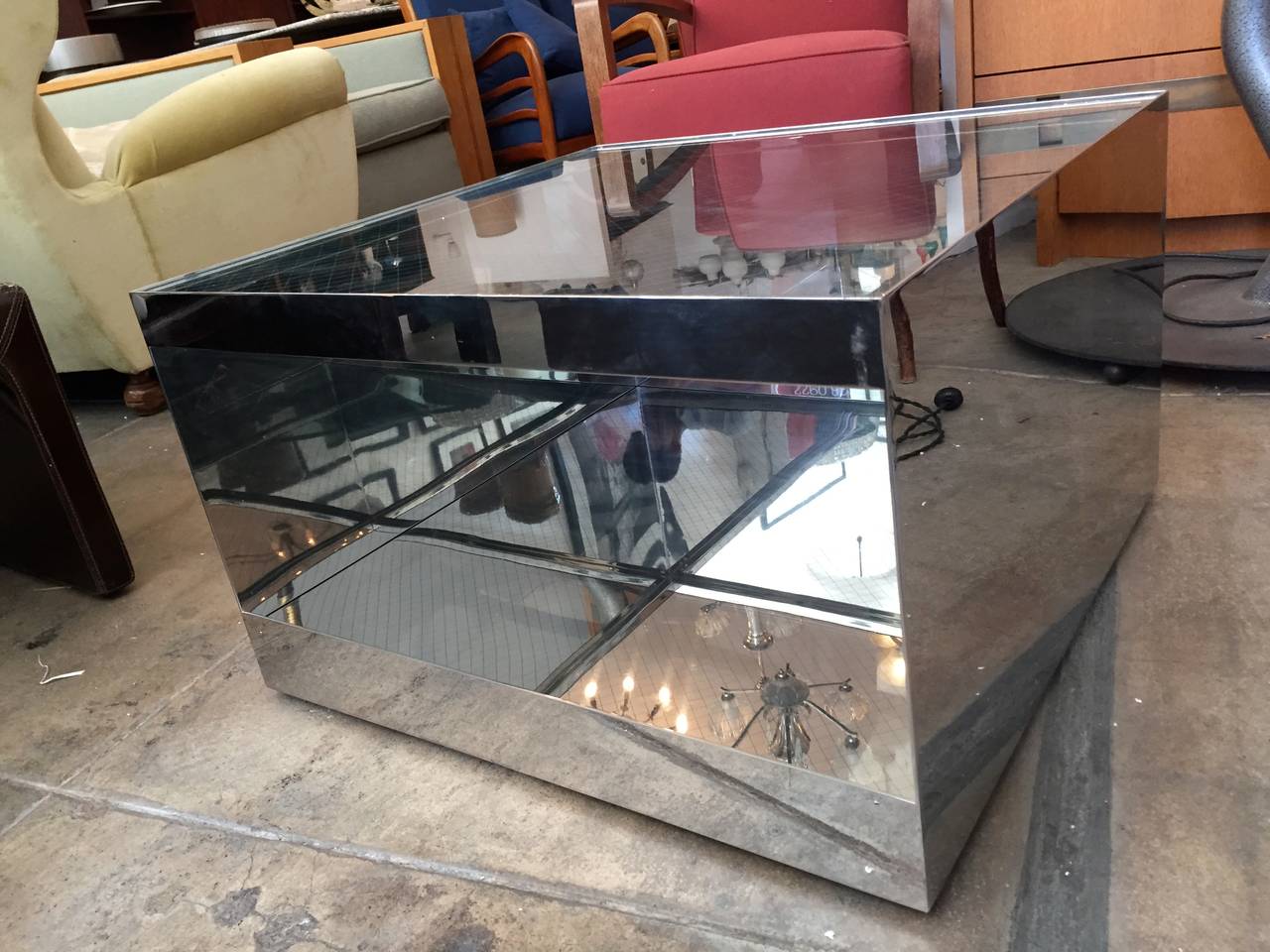 A sleek iconic polished steel and safety glass table designed by Joe D'urso for Knoll. This version is the medium coffee or side size 27" x 27". It open on one side allowing a shelf space and has bottom castors for easy movement.