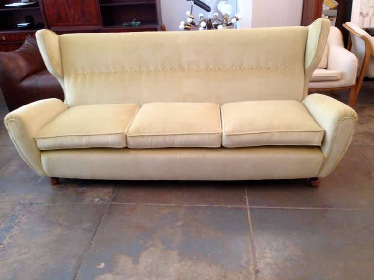 A large Italian 1940s moderne sculptural sofa with walnut rounded feet and a light yellow/green cotton velvet upholstery.