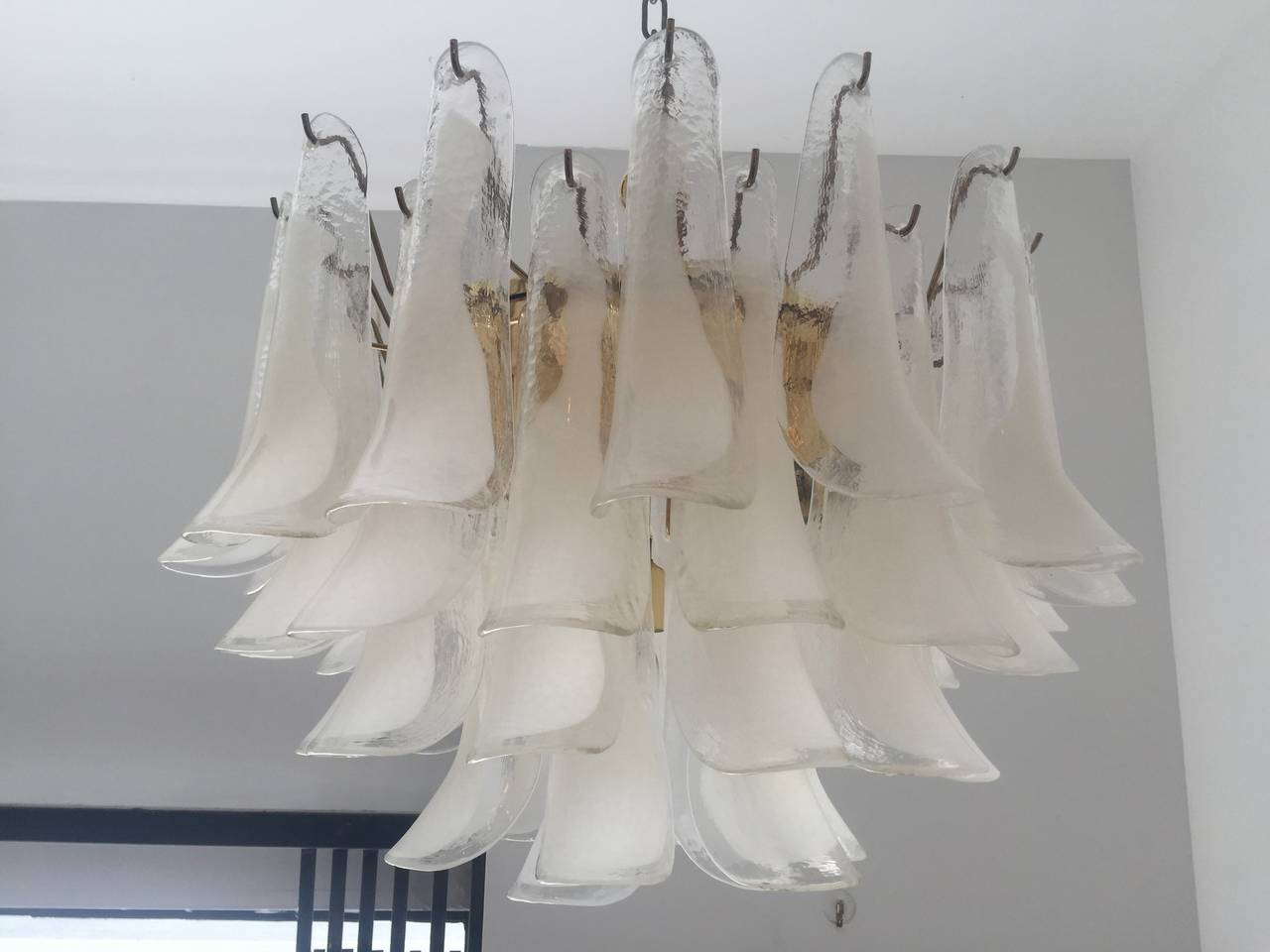 A wonderful warm blown Murano glass pendant composed of 47 white and clear petals on a polished brass frame. 11 light sources. Rewired . Matching canopy and extra chain for desired drop.