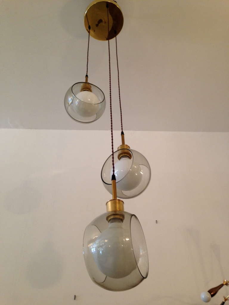 A wonderful 1960s three-light chandelier composed of a polished brass fixture, three smoked glass shades and brown silk wires. Rewired. Height can be adjusted.