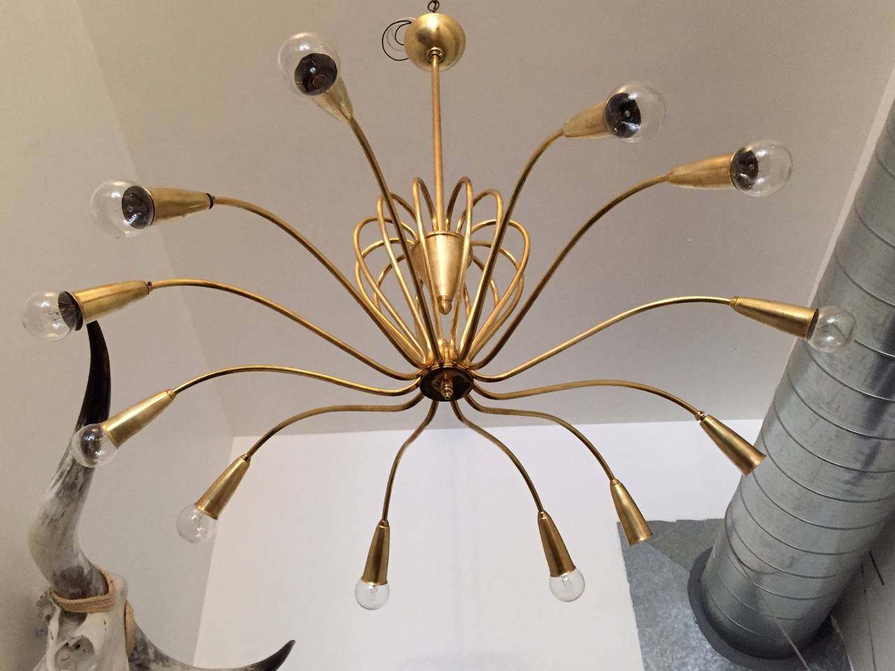 An original 1950s Italian large twelve-light satin brass chandelier with curved swooping arms. Rewired. Can be provided as a flush mount too.