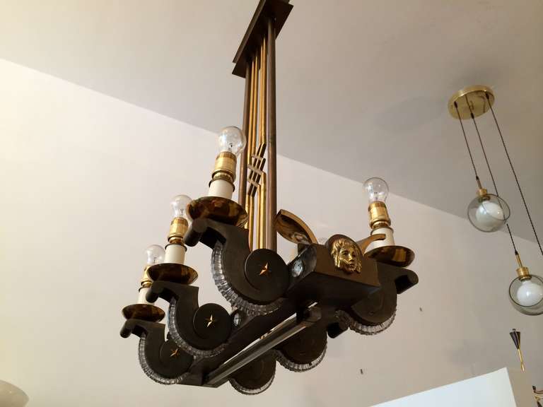 A great 1940s mixed metal and glass eight-light chandelier with decorative arms, brass stars and faces, and a solid glass rectangular rod. Rewired.