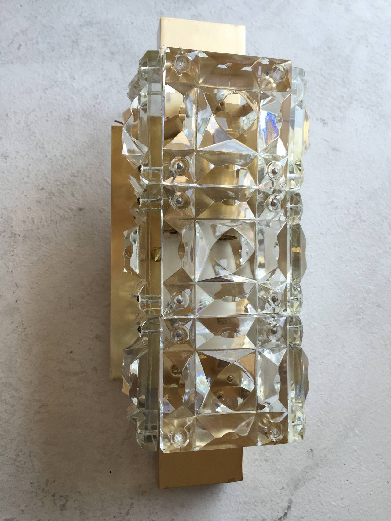 A luxurious pair of 1950s Austrian sconces composed of satin brass fixtures holding hand-cut thick crystal glass. Rewired. Made by Kinkeldey.