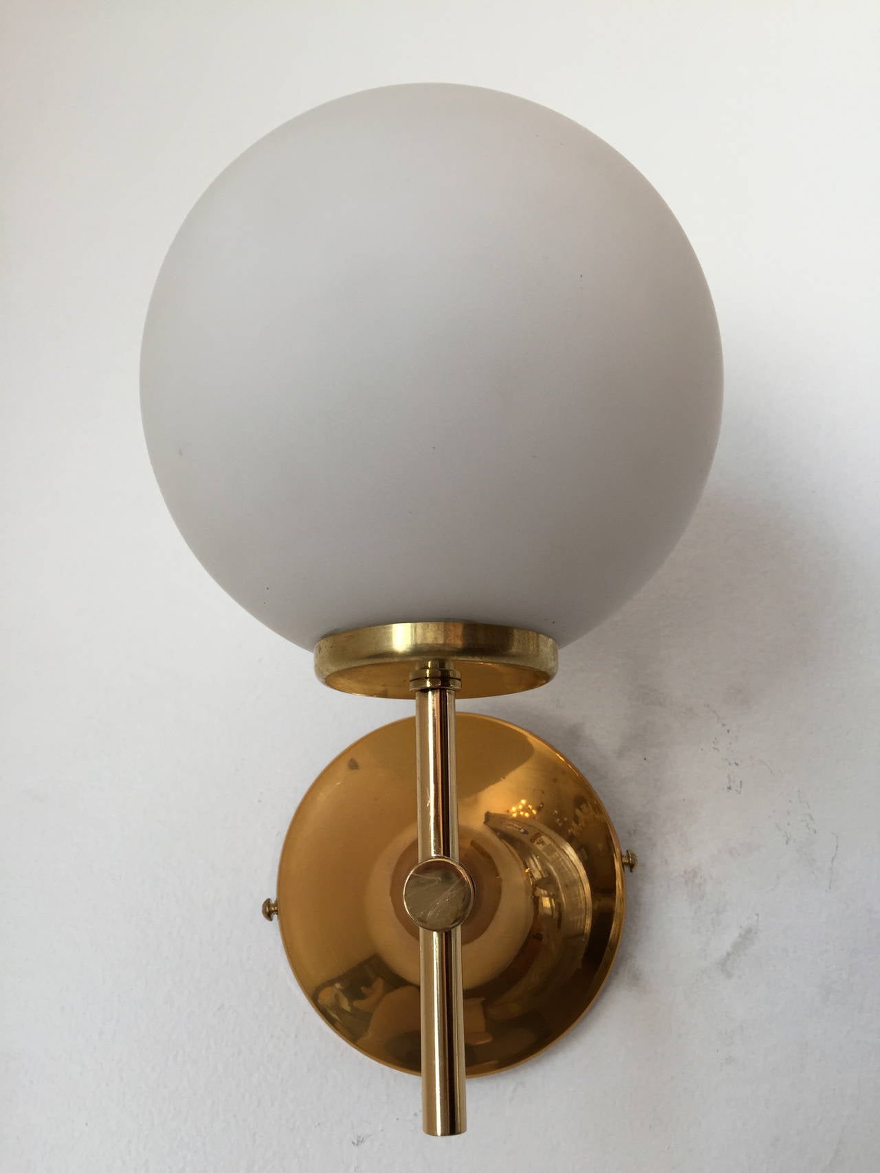 A nice set of Space-Age sconces composed of polished brass golden fixtures with white frosted glass globe shades. Rewired.
