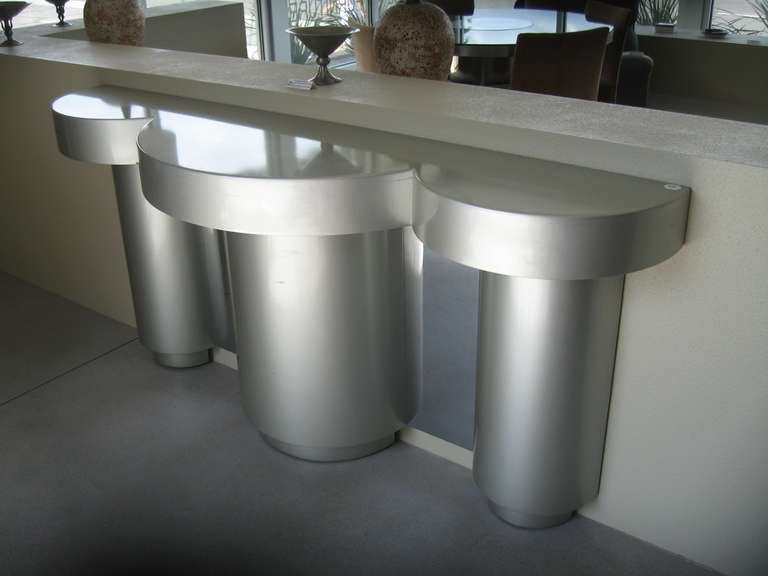 A high glass silver lacuered Futurist console table with a chrome backplate by New York designer, Ernest C. Masi.